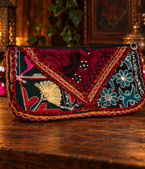 Bolsa de mão bordô e verde com bordados florais e geométricos, zíper preto e detalhes pendentes coloridos, vista de frente